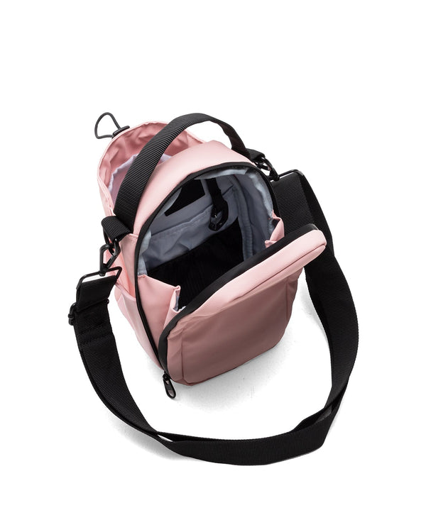 Pink crossbody bag with black strap on a white background