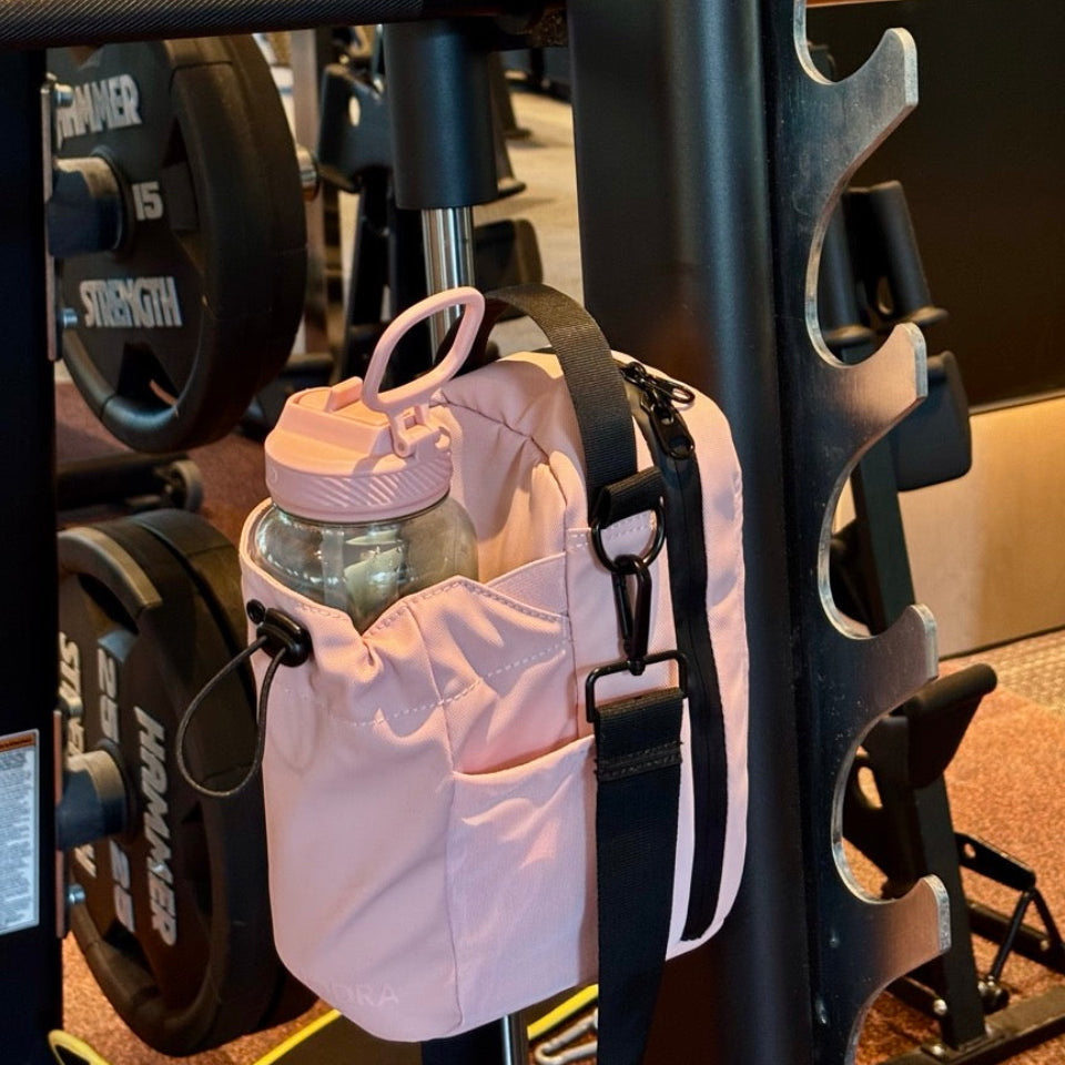 Pink water bottle magnetic holder attached to a weight rack in a gym.